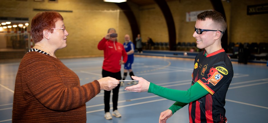 Mona Wejlgaard overrækker donationen på 3.000 kr. til Denis Prce fra Skjern, der er en af de syv udtagne Special Olympics-spillere, der skal repræsentere Danmark i herrehåndbold ved Special Olympics World Games i Berlin i 2023. Foto: Thomas Sjørup.